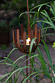 Rusty candle holder with a burning candle in the garden