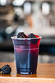 Blackberry soda with ice cubes in a plastic cup