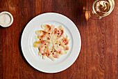 Fish carpaccio with red peppercorns served with a glass of white wine