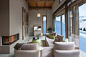 Elegantes Wohnzimmer in hellen Tönen mit Panoramablick auf verschneite Berglandschaft