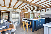 Essbereich und Mittelblock in offener Küche mit Holzbalkendecke