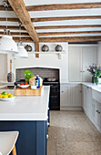 Central unit with blue fronts in open-plan kitchen with wood-beamed ceiling