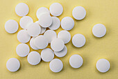 White pills capsules on yellow bacground