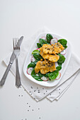 Fried hake fillet on a spinach and radish salad