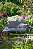 Gartensitzplatz vor Blumenbeeten mit Kugellauch (Allium sphaerocephalon), Stauden-Phlox (Phlox paniculata), Duftnessel (Agastache)
