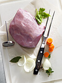 Raw pork with a meat fork, meat thermometer and vegetables