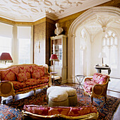 Italian gilt sofa and chairs with damask pattern in living room with original Gothic arch and black and gold wallpaper