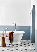 Free-standing bathtub with side table in bathroom with marble floor tiles