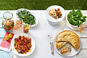 Kartoffel-Schinken-Pie, Blattsalat, Tomaten-Karotten-Salat, grüne Bohnen mit Senf und Limonade