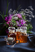 Honey in jars in front of a bouquet of flowers