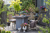 Garden table with Easter decorations, cake, Easter nest with eggs and flower pots