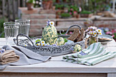Kräuterbutter in Eiform mit Schnittlauch, Petersilie, Knoblauch, Thymian, dekoriert mit Gänseblümchen auf Terrassentisch