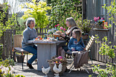 Frauen und Kind beim Osterfrühstück am gedeckten Tisch auf der Terrasse