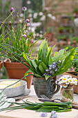 Bärlauchblätter, Gänseblümchen in Vase, Schnittlauch im Topf, Butterschale, Zutaten für die Herstellung von Kräuterbutter