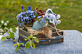 Easter nest with egg, feather, grape hyacinth (Muscari), forget-me-not, horned violet (Viola Cornuta) and twig
