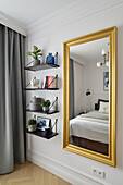 Gold-framed mirror and shelves on the wall in the bedroom