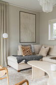 Sitting area in beige with cushions and curved shaped coffee table