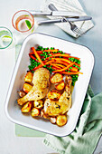 Roasted chicken legs with potatoes, peas, and carrots
