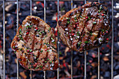 Grilled neck steaks of pork on a grill grate