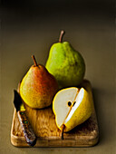 Three kinds of pears on a small chopping board with a knife