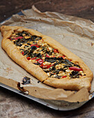 Oval flat bread with peppers, cheese, onions and spinach
