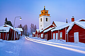 Autolichter auf der vereisten Straße, die durch die mittelalterliche, verschneite Gammelstad-Kirchenstadt führt, UNESCO-Weltkulturerbe, Lulea, Schweden, Skandinavien, Europa