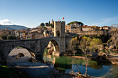 Besalu historische mittelalterliche Stadt mit katalanischen Flaggen auf dem steinernen Brückenturm über den Fluss El Fluvia, Besalu, Katalonien, Spanien, Europa