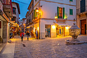 View of shops in narrow street in the old town of Pollenca at dusk, Pollenca, Majorca, Balearic Islands, Spain, Mediterranean, Europe