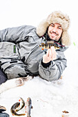 Portrait of smiling man holding a fish caught after ice fishing, Lapland, Sweden, Scandinavia, Europe