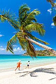 Frau und kleiner Junge haben Spaß beim Laufen an einem palmengesäumten Strand, Antigua, Westindische Inseln, Karibik, Mittelamerika