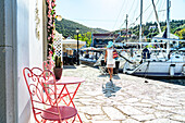 Frau schaut auf Segelboote im kleinen Hafen des Küstendorfes Fiskardo, Kefalonia, Ionische Inseln, Griechische Inseln, Griechenland, Europa