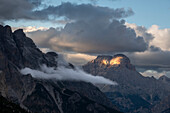 Sonnenuntergang mit Wolken auf der Rotwand in den Dolomiten mit einem einzelnen Lichtstrahl auf dem Felsen, Dolomiten, Italien, Europa