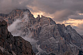 Sunset light above Tofane with some low clouds hanging between rocks, Dolomites, Italy, Europe