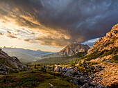 Sonnenuntergang über dem Berg Conturines mit farbigen Wolken am Himmel und goldenem Licht auf den Kiefern und im Tal, Dolomiten, Italien, Europa