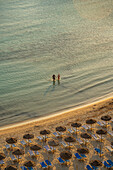 Blick auf ein Paar im Meer und Sonnenschirme am Platja de Cala Galdana in Cala Galdana, Cala Galdana, Menorca, Balearen, Spanien, Mittelmeer, Europa