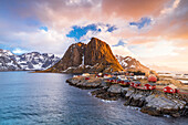 Wolken bei Sonnenaufgang über traditionellen Rorbu-Häusern auf Klippen am kalten arktischen Meer, Hamnoy, Reine, Lofoten, Norwegen, Europa