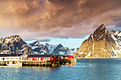Storm clouds at dawn over mountain peaks and fishing village of Sakrisoy, Reine, Nordland county, Lofoten Islands, Norway, Europe
