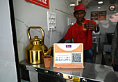 Chai wallah serving chai in old style terracotta disposable cups, with 21st century sign for payment by mobile phone, Mahisagar, Gujarat, India, Asia
