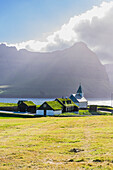 View of the church and grass roof houses in the village of Vidareidi at sunset, Vidoy island, Faroe Island, Denmark, Europe