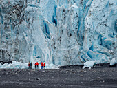 Touristen stehen vor dem Aialik Glacier, der aus dem Harding Ice Field kommt, Kenai Fjords National Park, Alaska, Vereinigte Staaten von Amerika, Nordamerika