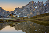 Segantini mountain hut reflected in a lake, Rolle Pass, Dolomites, Trentino, Italy, Europe