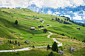 Wanderer auf Wanderweg zwischen grünen Feldern und Holzhütten, Sass de Putia, Passo delle Erbe, Dolomiten, Südtirol, Italien, Europa