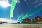 Wellen des eisigen Meeres beleuchtet von Mond und grünen Lichtern der Aurora Borealis (Nordlichter), Haukland Strand, Leknes, Lofoten Inseln, Norwegen, Skandinavien, Europa