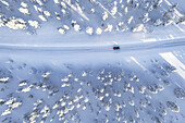 Overhead view of car driving on winding road in the winter forest covered with snow, Kangos, Norrbotten County, Lapland, Sweden, Scandinavia, Europe