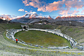 Mann genießt den Blick auf das alte Amphitheater und den verschneiten Gipfel bei Sonnenuntergang, Alba Fucens, L'Aquila, Apennin, Abruzzen, Italien, Europa