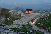 Hiker stands on the trail to the Duca degli Abruzzi mountain hut at dusk, Campo Imperatore, Apennines, Abruzzo, Italy, Europe
