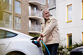 Senior man charging electric car