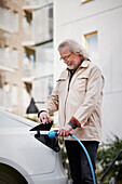 Senior man charging electric car