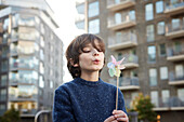 Boy blowing on pinwheel outdoors
