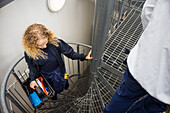 Young female technician carrying tool box on stairs